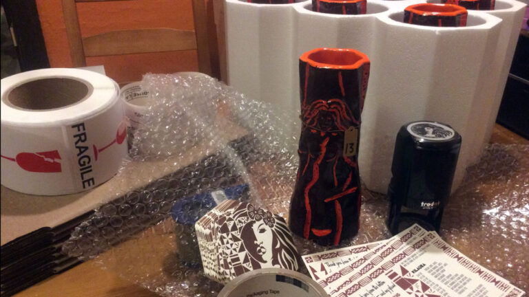 Lava-glazed Pele tiki mug tagged number 13 amid foam shipping inserts, bubble wrap, coasters, and FRAGILE stickers