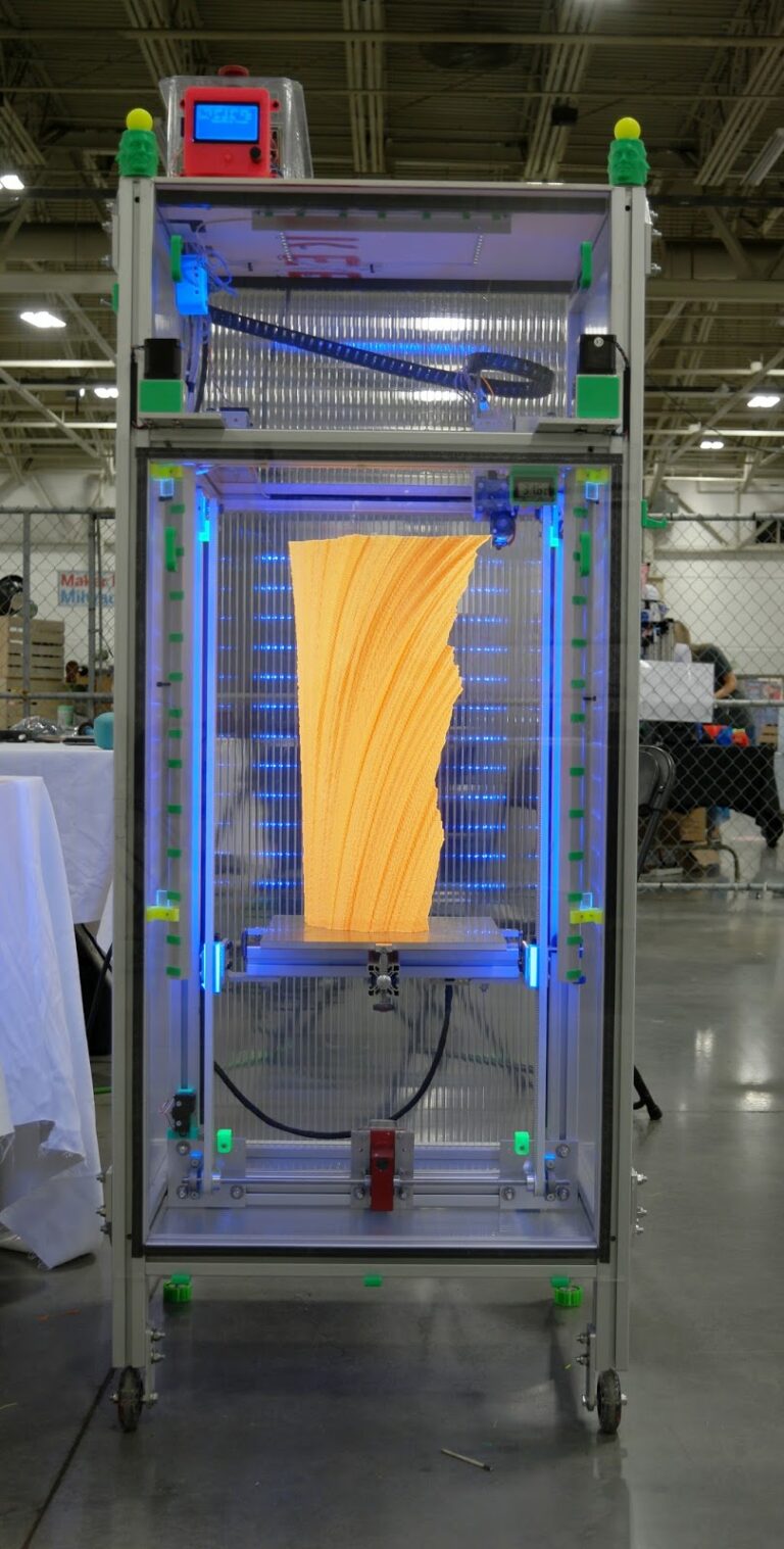 Tall enclosed 3D printer with blue LED lighting printing a large spiral orange vase at a maker faire